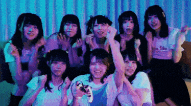 a group of girls are posing for a picture and one girl is holding a video game controller