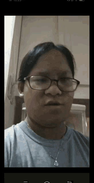 a woman wearing glasses and a necklace looks at the camera with a serious look on her face