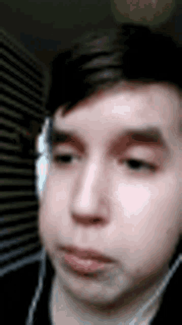 a close up of a young man wearing headphones and looking at the camera .