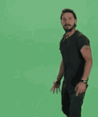 a man in a black shirt is standing in front of a green background .