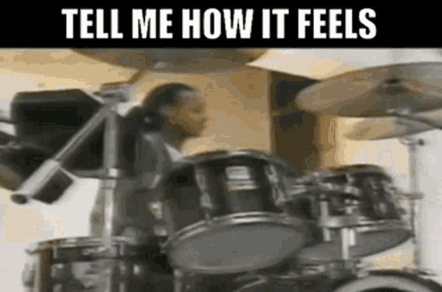 a man is playing drums in a room with the words `` tell me how it feels '' .
