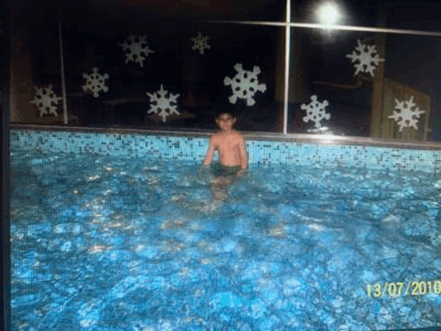 a boy is swimming in a swimming pool with snowflakes on the wall .