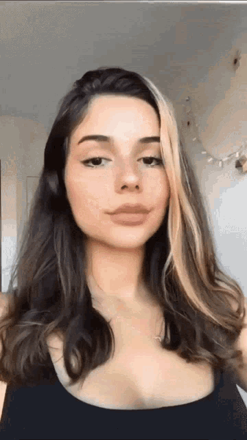 a woman with long brown hair and a black tank top