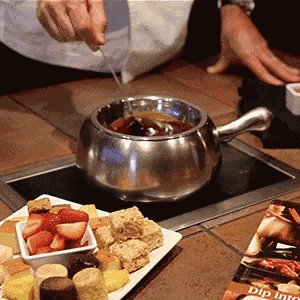 a person dipping a spoon into a pot of sauce