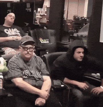 three men are sitting in chairs with one wearing a hoodie that says draft kings on it