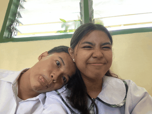 a boy and a girl are posing for a picture and making funny faces