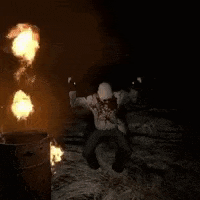 a clown is standing in front of a barrel of flames .