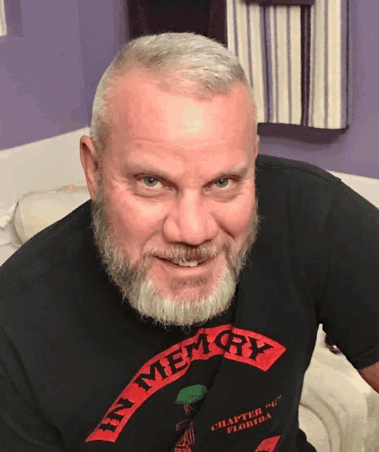 a man with a beard wearing a black shirt that says in memory