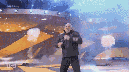 a man is standing on a stage holding a microphone in front of a crowd .