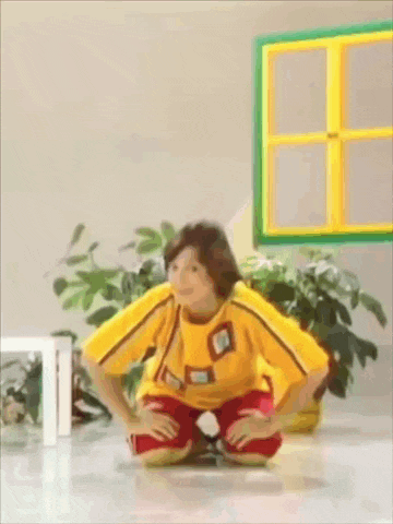 a child in a yellow shirt and red pants is kneeling down on the floor .
