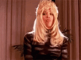 a woman wearing a wig and a catsuit is making a face .