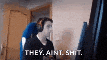 a man wearing headphones is sitting in front of a computer screen and saying `` they ain 't shit '' .