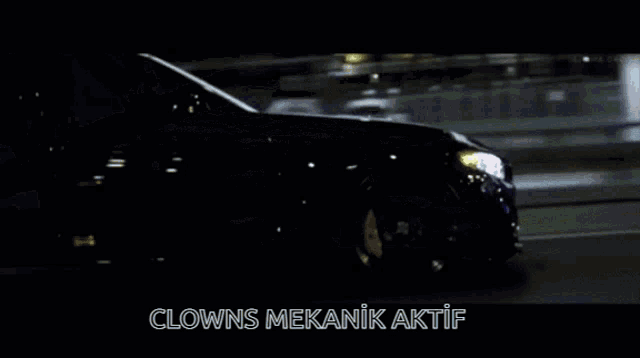 a car is driving down a street at night and the words clown 's mekanik aktif are on the screen