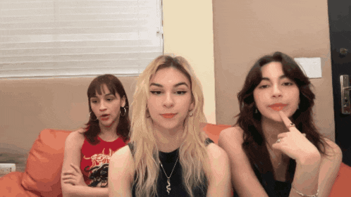 three girls are sitting on a couch and one has a shirt on that says ' slayer '