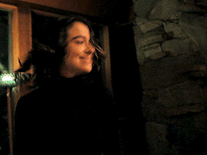a woman in a black turtleneck is smiling while a man in a suit looks on