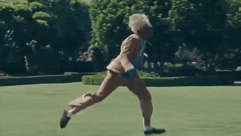 a man in a suit and tie is dancing in a park .