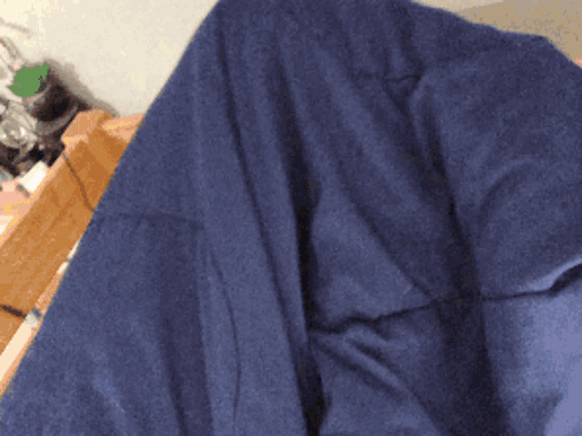 a person laying on a bed with a blue blanket covering their face