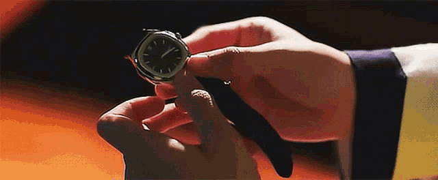 a close up of a person holding a watch with the hands on the numbers 12 and 5