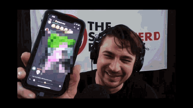 a man wearing headphones is holding up a cell phone in front of a banner that says the nerd