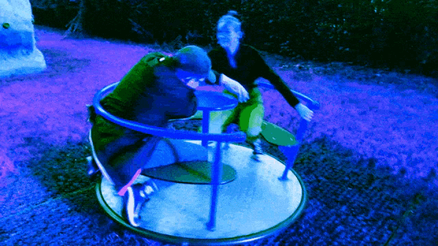 two people are playing on a merry go round in a blue light