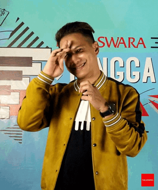 a man wearing a yellow jacket stands in front of a sign that says swara angga