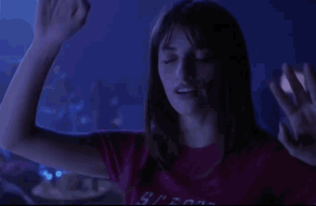 a woman in a dark room with a purple shirt on