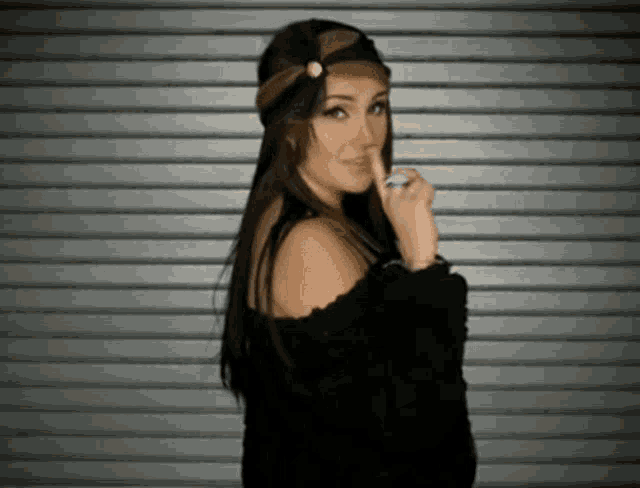 a woman wearing a headband and a ring holds her finger to her mouth