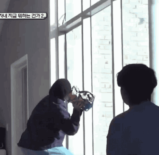 two people standing in front of a window with a sign that says " 2 " on it