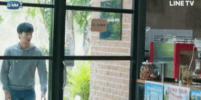 a man is standing in front of a closed sign in a store .