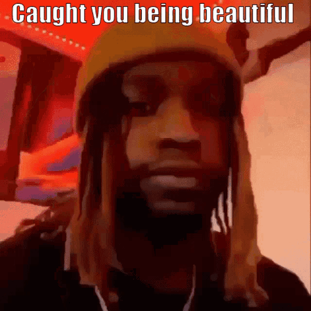 a man with dreadlocks wearing a yellow hat with the words caught you being beautiful