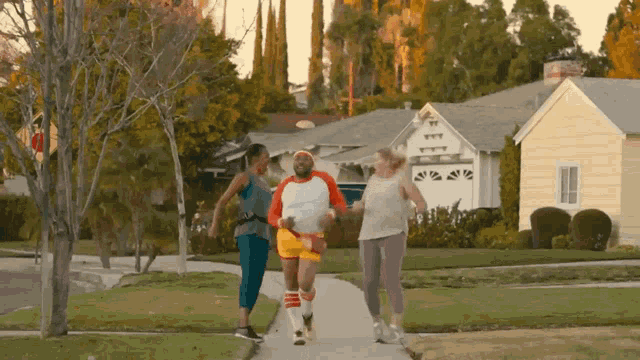 a group of people are running down a sidewalk in front of houses