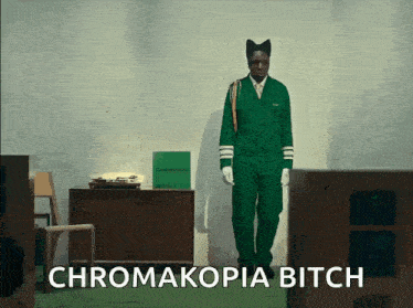 a man in a green uniform is standing in a room with the words chromakopia bitch above him