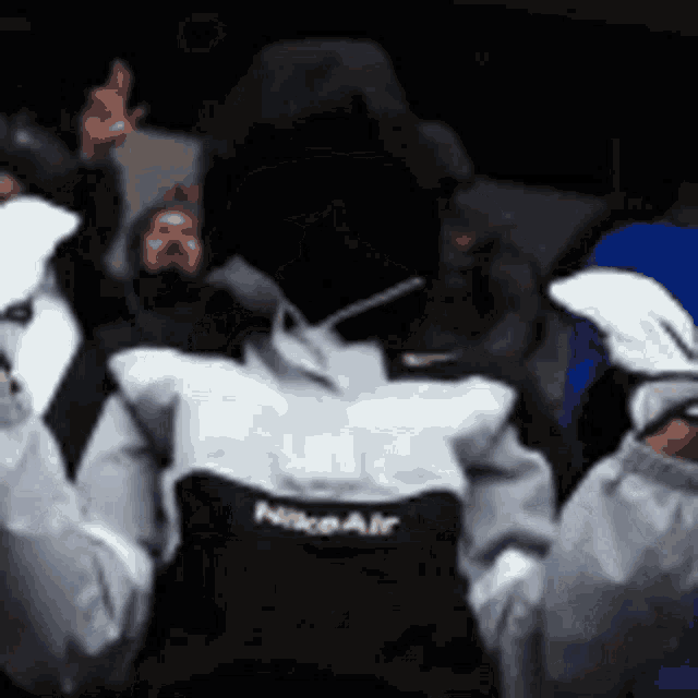 a person wearing a nike air jacket is standing in a crowd of people