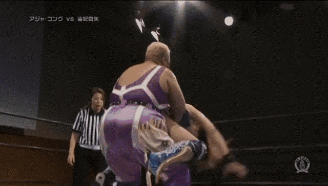 two women are wrestling in a ring with a referee standing behind them