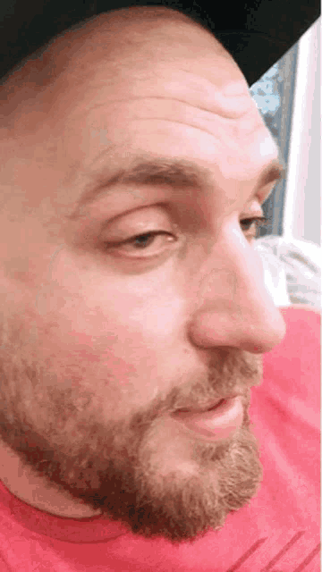 a man with a beard is wearing a red shirt and a hat