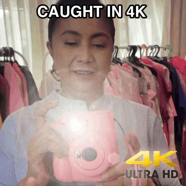 a woman taking a picture with a pink camera and the words caught in 4k above her