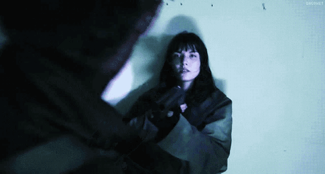 a woman in a green jacket is being held by a man in a dark room with bbcnet written above her