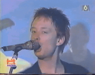 a man is singing into a microphone with the word hit on the bottom right