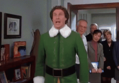 a man in a green elf costume is standing in front of a group of people in an office .