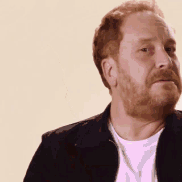 a man with red hair and a beard is wearing a black jacket
