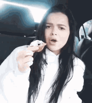 a woman is sitting in a car eating a donut with a fork .