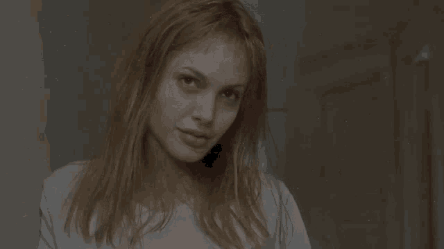 a woman with long blonde hair is wearing a white shirt .