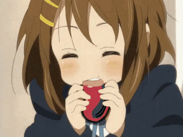 a girl in a school uniform is holding a red object in her mouth