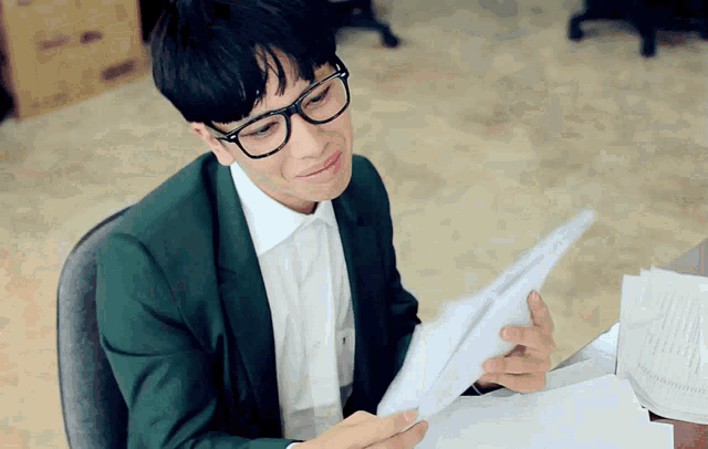 a man wearing glasses is sitting at a desk with papers