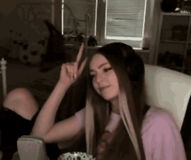a woman in a pink shirt is giving a peace sign
