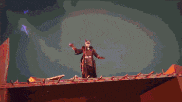 a man in a robe is standing on top of a building with a purple background