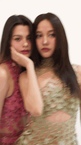 a blurry picture of two women standing next to each other on a white background .
