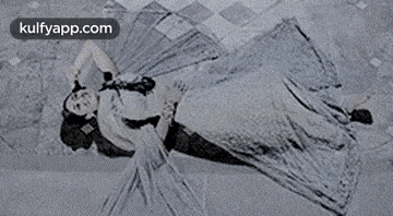 a black and white photo of a woman laying on the floor with a man holding her .
