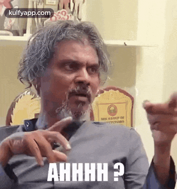a man with gray hair and a beard is making a funny face while talking to someone .