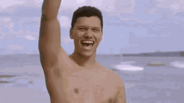 a man without a shirt is standing in front of a row of surfboards .
